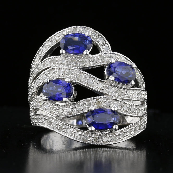 A vintage sapphire and diamond ring with a cascading design, featuring blue sapphires and round diamonds set in 14K white gold.