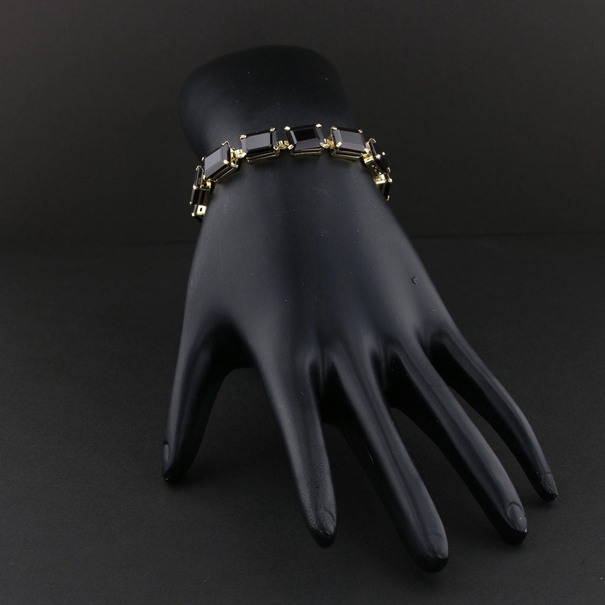 Garnet line bracelet on a black display hand. Item 894562.