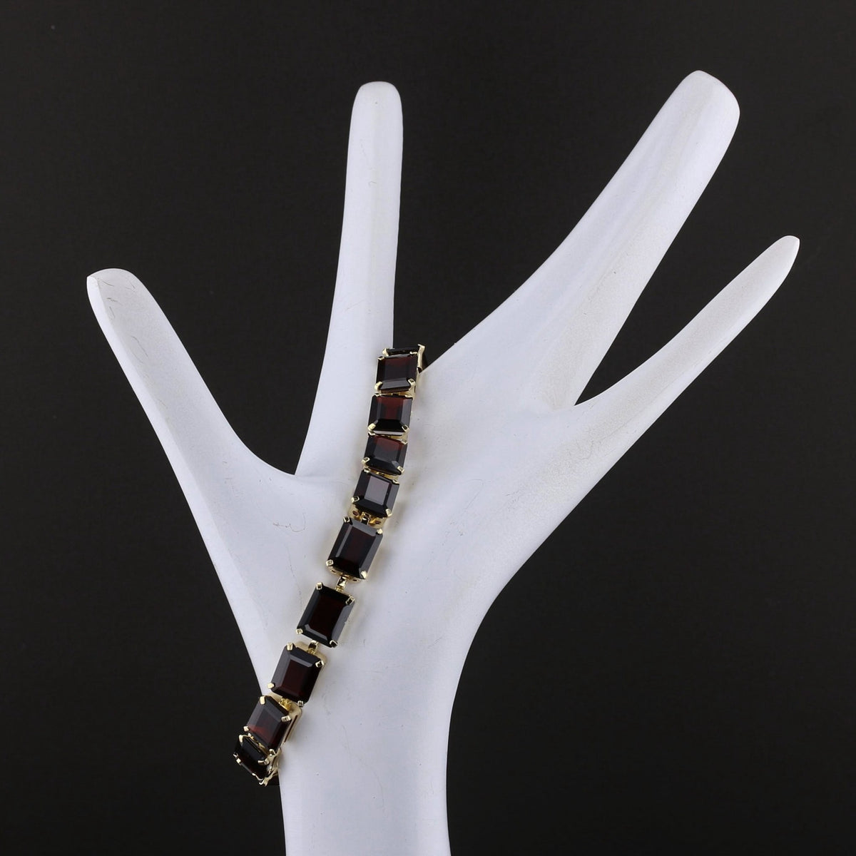Garnet line bracelet draped on a display hand, side view. Item 894562.