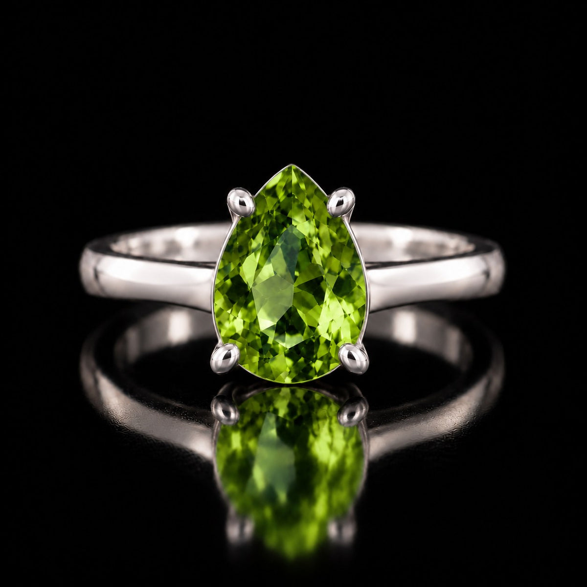 The same VooDooStone pear-cut solitaire ring turning peridot green under fluorescent light, front view. Item 894782.