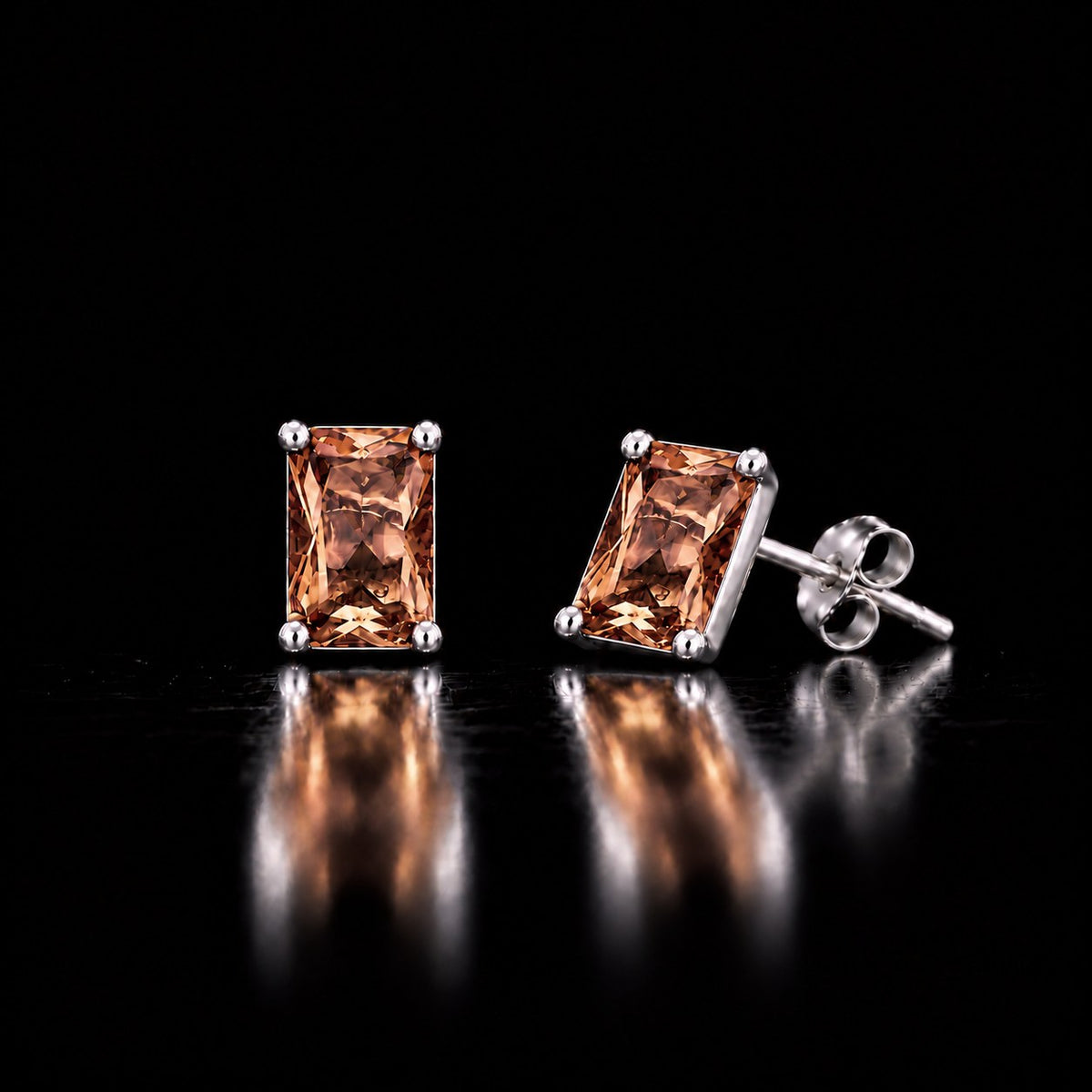 Pair of sterling silver VooDooStone emerald-cut stud earrings, rectangular step-cut stones golden amber under warm incandescent light. Item 894789.