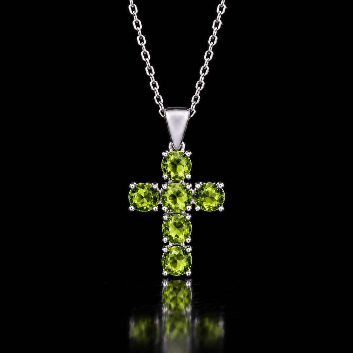 The same VooDooStone cross pendant turning peridot green under fluorescent light. Chain shown for scale, not included. Item 894790.