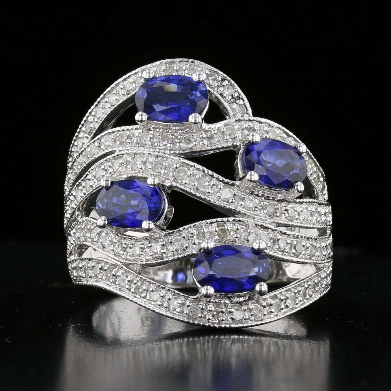 A vintage sapphire and diamond ring with a cascading design, featuring blue sapphires and round diamonds set in 14K white gold.