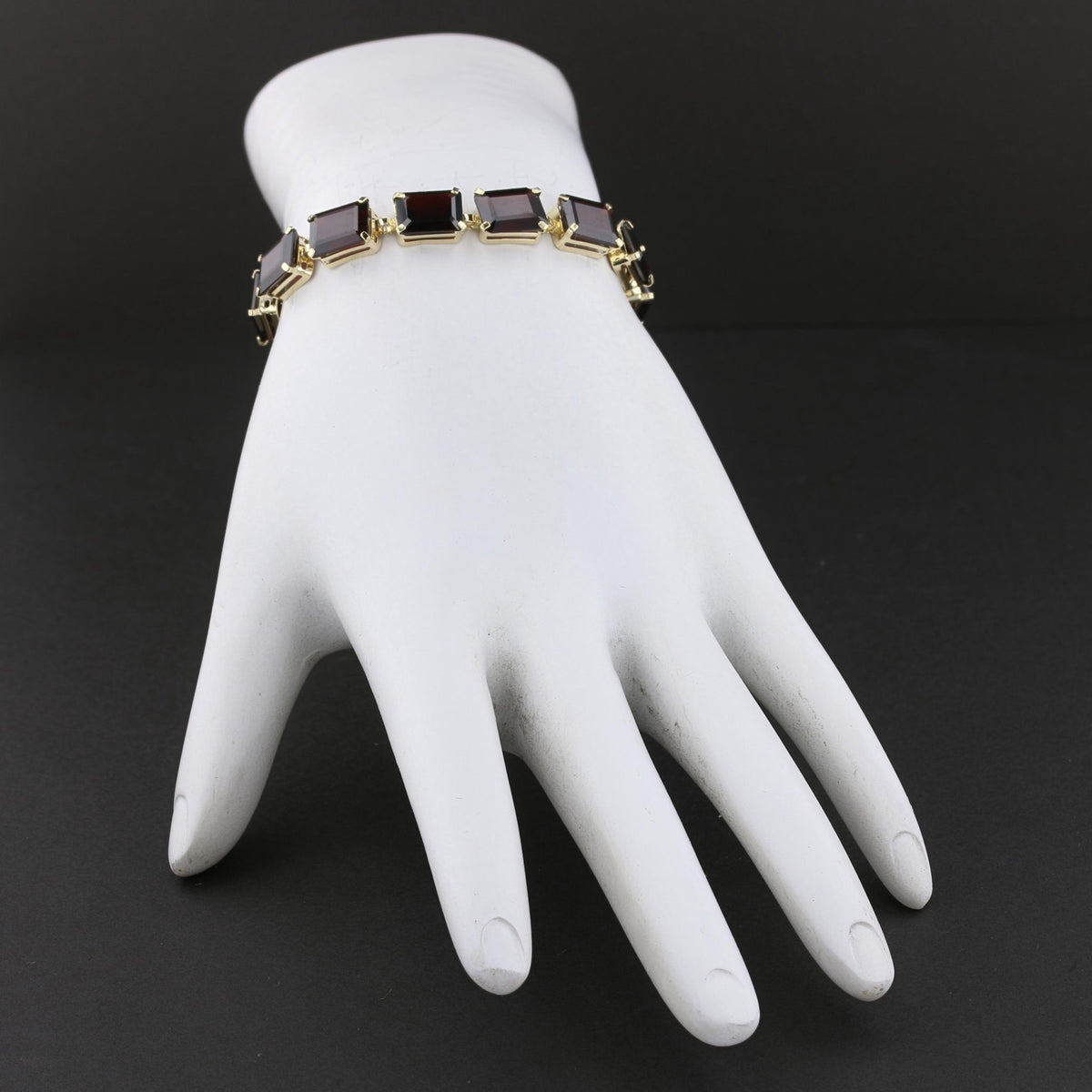 Garnet line bracelet worn on a white display hand. Item 894562.