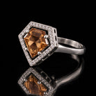 The same VooDooStone shield-cut halo ring turning golden amber under warm incandescent light, front view. Item 894784.