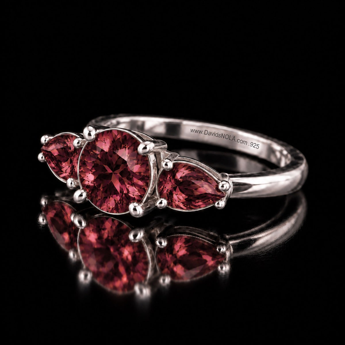 Sterling silver VooDooStone three-stone ring in purplish-pink daylight colour, angled view showing the slim band. Item 894786.