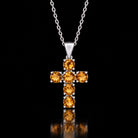 The same VooDooStone cross pendant turning golden amber under warm incandescent light. Chain shown for scale, not included. Item 894790.