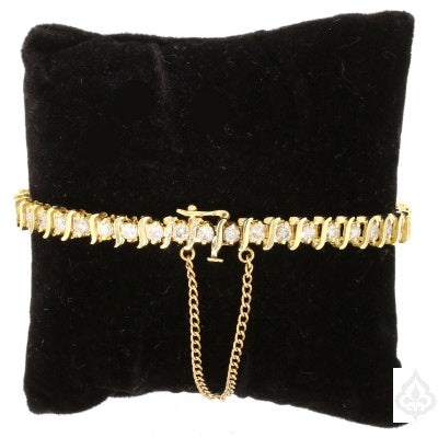 Gold bracelet closed and looped around a black cushion 
